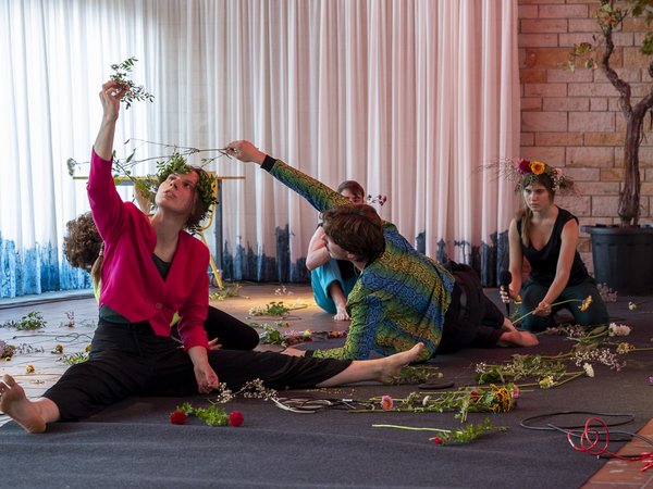 Vier junge Frauen performen auf dem Boden mit Blumen